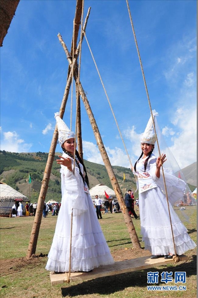 两名牧民身着吉尔吉斯斯坦民族服装在帐篷前游戏