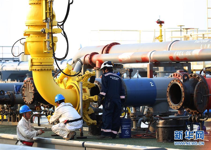 工作人员帮助卸油臂与油轮原油管口对接。