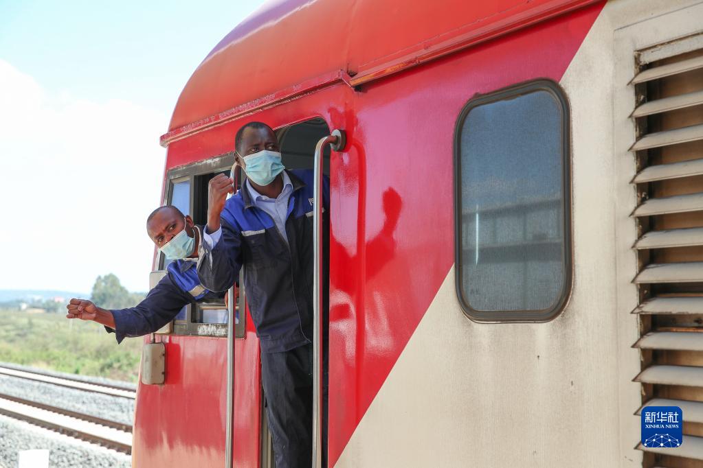 3月25日，在肯尼亚恩贡站，正司机约翰（左）和副司机布赖恩与站台工作人员确认安全。新华社记者 龙雷 摄