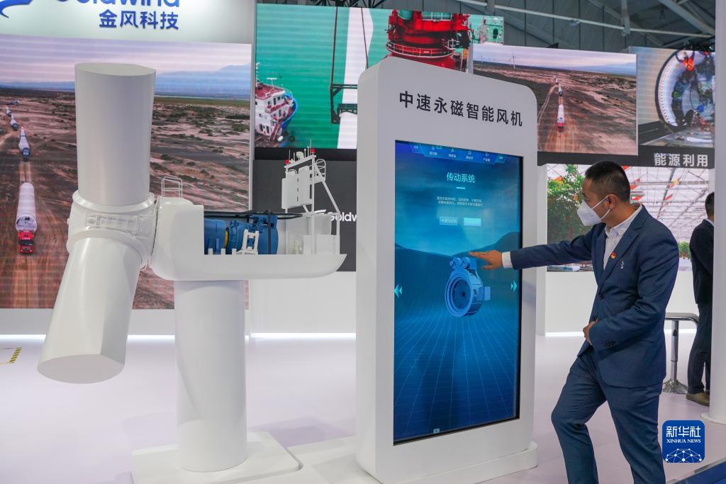 9月21日，在第七届中国－亚欧博览会上，新疆金风科技股份有限公司展位的工作人员在介绍中速永磁智能风机。新华社记者 丁磊 摄