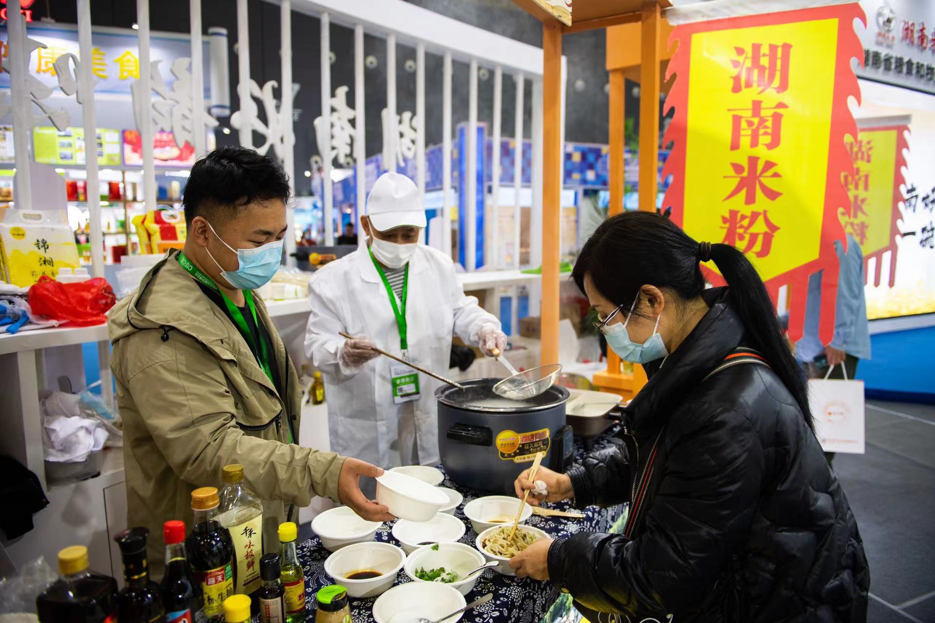11月24日，在长沙国际会展中心，观众在品尝特色食品。新华社记者 陈思汗 摄