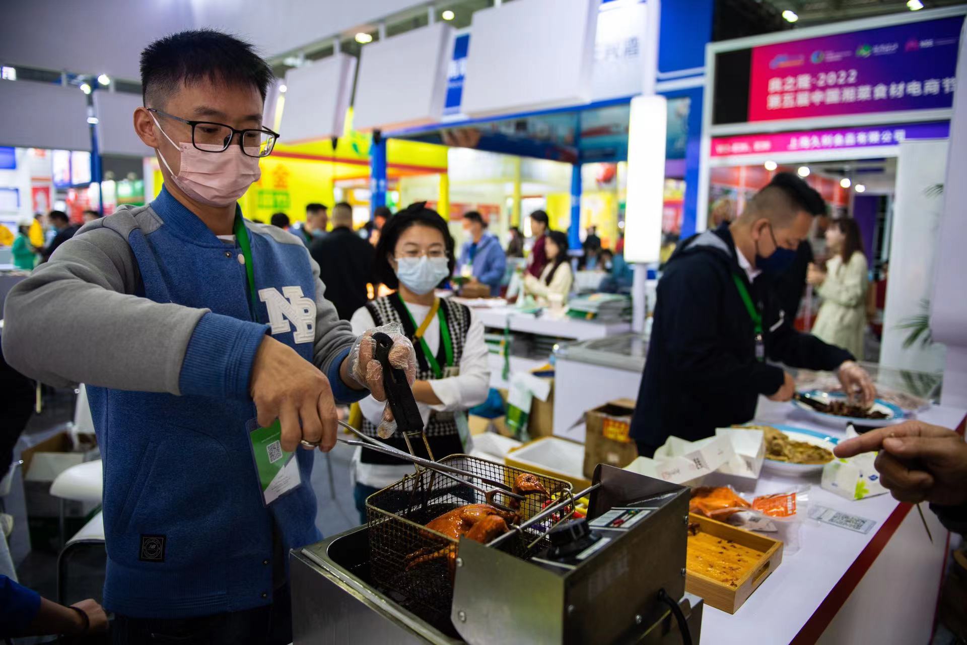 11月24日，在长沙国际会展中心，工作人员（左）在制作食品供观众品尝。新华社记者 陈思汗 摄